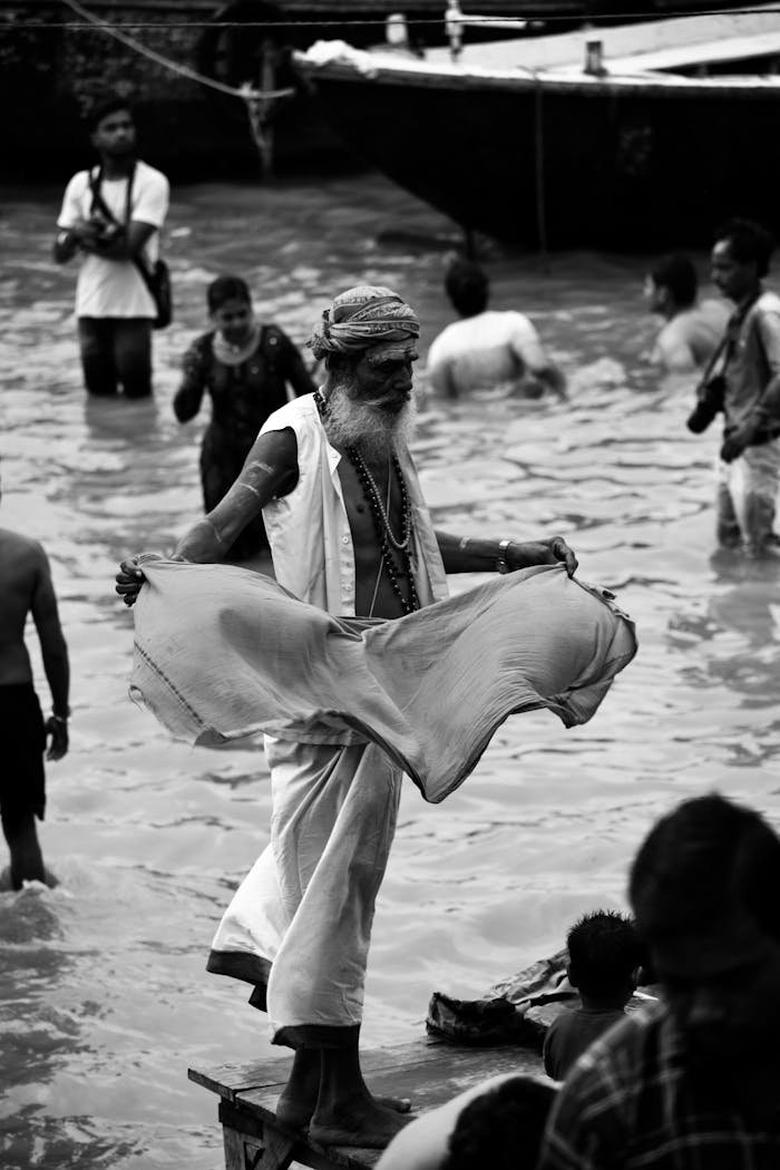 A black and white image of a sadhu performing a purification ritual in the Ganges River, India.