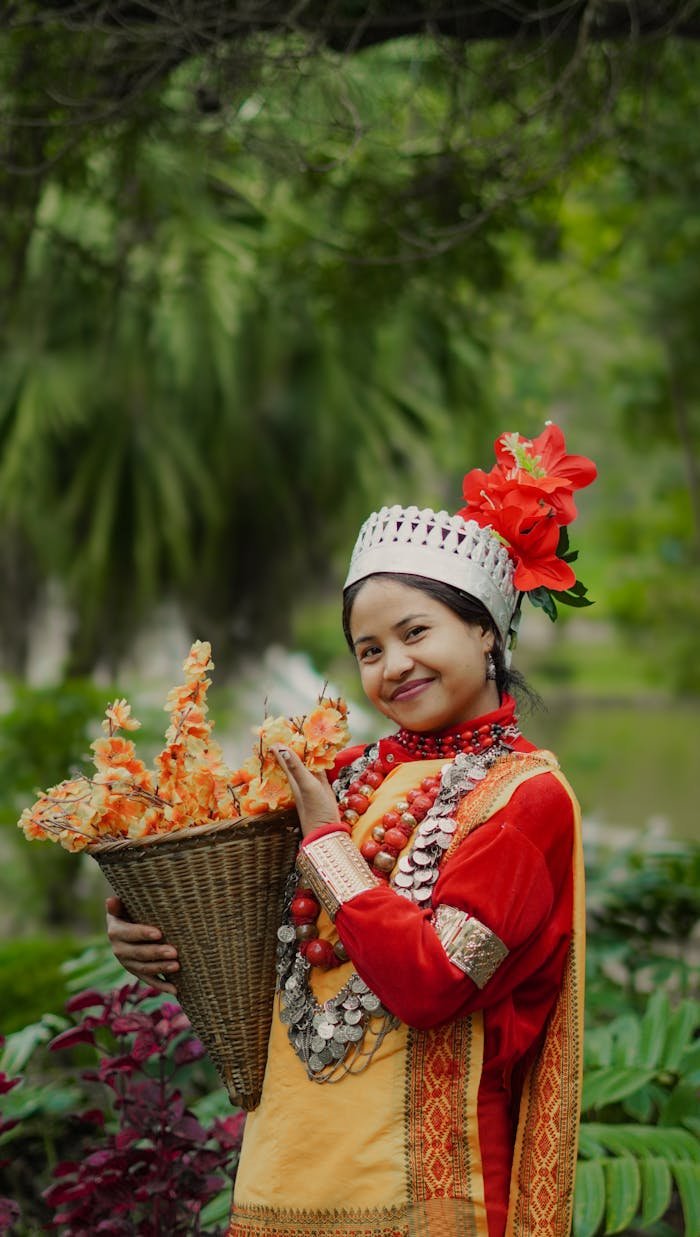 A smiling woman in traditional Meghalayan attire holding a basket of orange flowers outdoors.