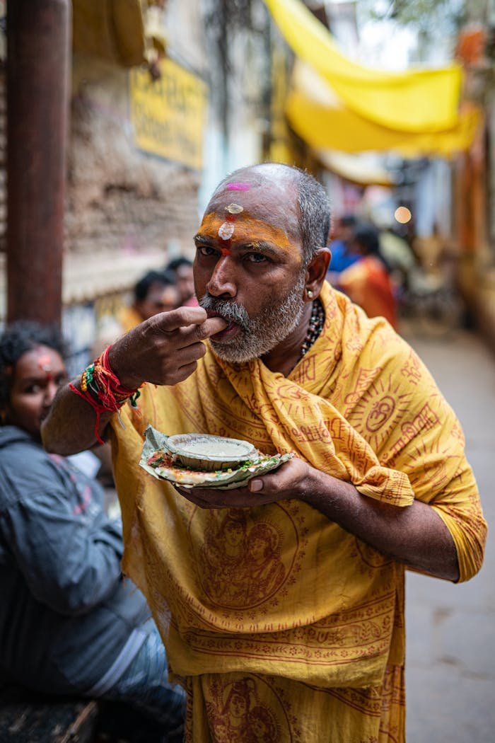 A South Asian man eats traditional food in the streets of Varanasi, India.